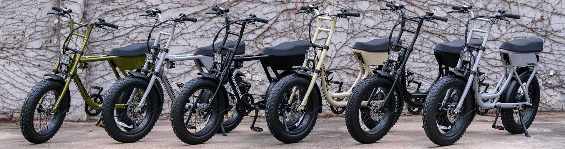 Row of Grandeux electric bikes parked against a textured wall.